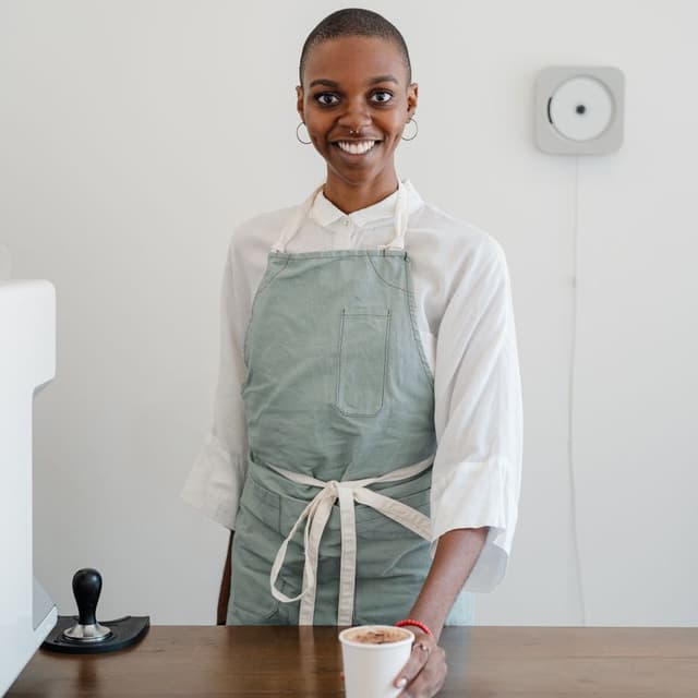 Portrett av kafévert i forkle med en kopp kaffe