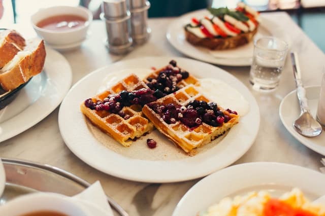 Vafler med friske bær og krem på et dekket frokostbord